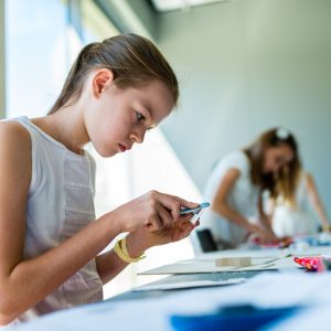 Young girl learning on the course of architectural design for children - preparing architectural model