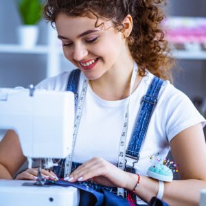 The happy woman working near the sewing machine