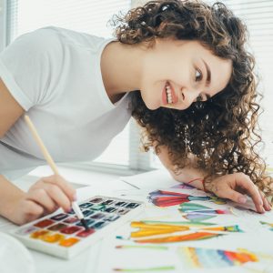 The attractive artist painting a picture at the table